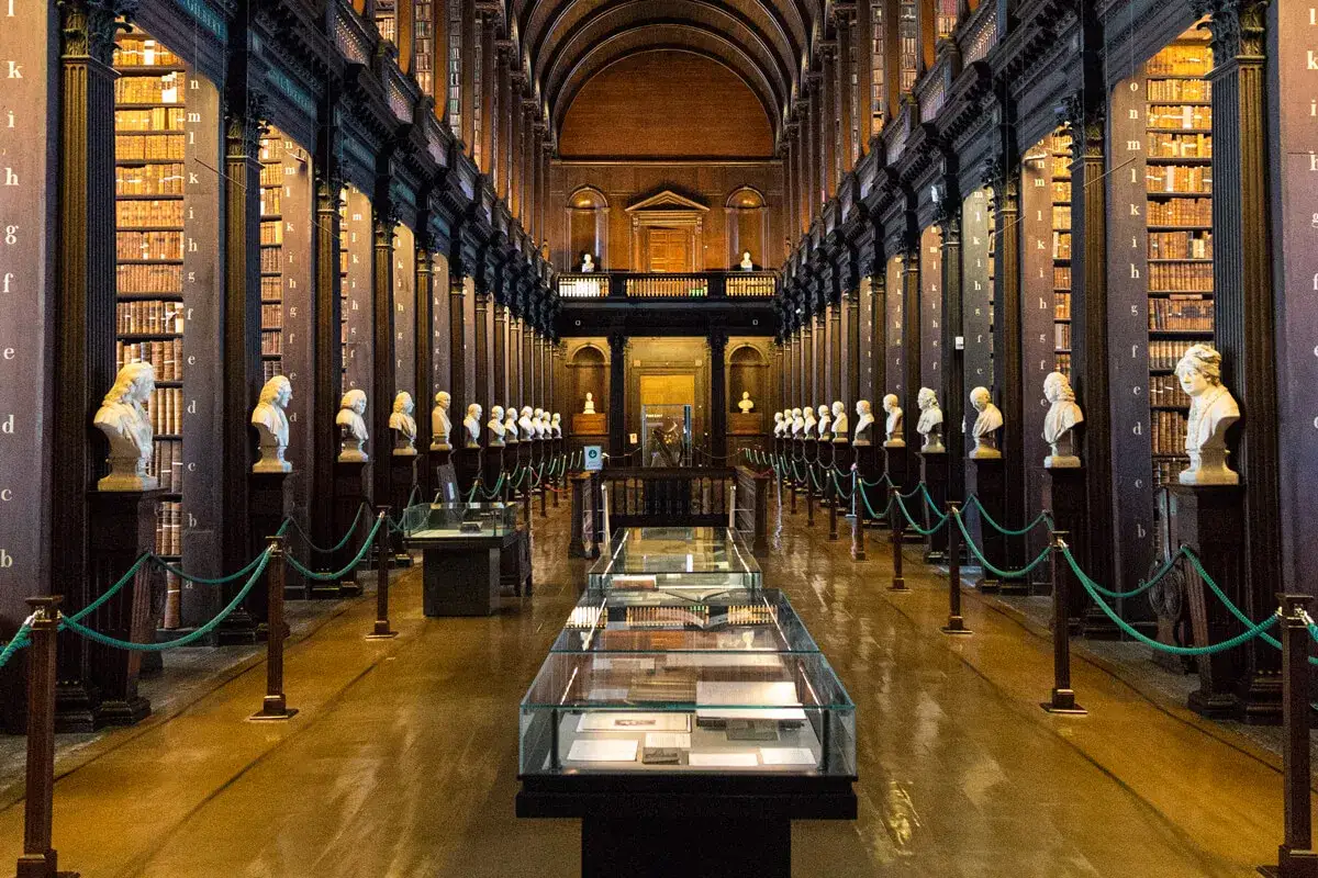 La Gran Sala de la Biblioteca del Trinity College, donde se exhibe el libro de Kells, con bustos de m&aacute;rmol y estanter&iacute;as repletas de libros antiguos.